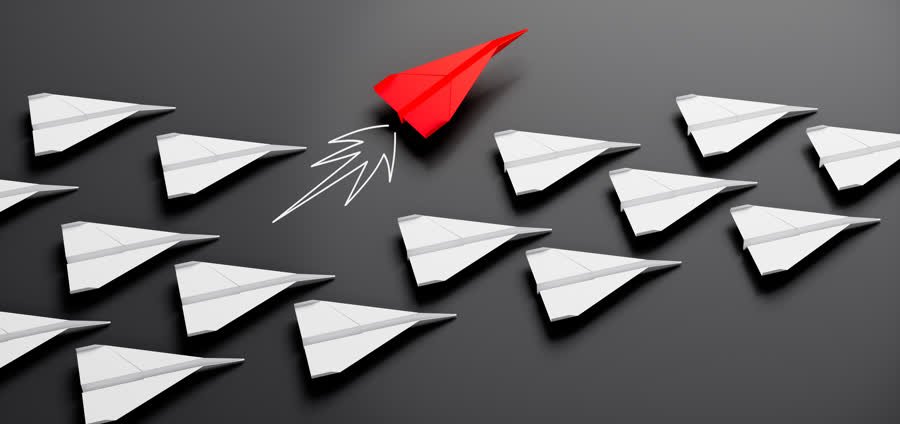 Avión de papel rojo destacando en una formación de aviones blancos